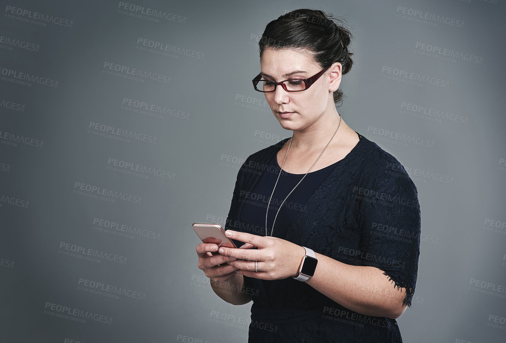 Buy stock photo Studio shot of a young businesswoman using a mobile phone against a grey background