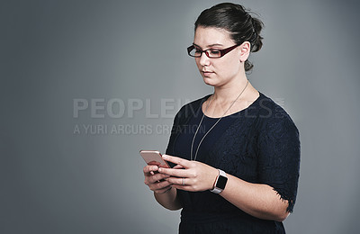 Buy stock photo Studio shot of a young businesswoman using a mobile phone against a grey background