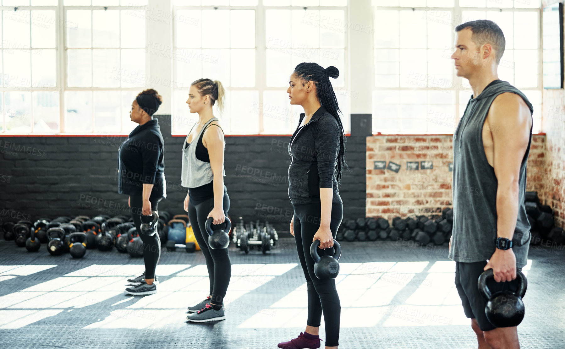 Buy stock photo Shot of a fitness group using dumbbells in their session at the gym