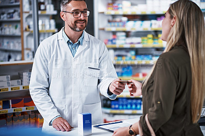 Buy stock photo Shot of a young woman paying for merchandise with a credit card at a pharmacy