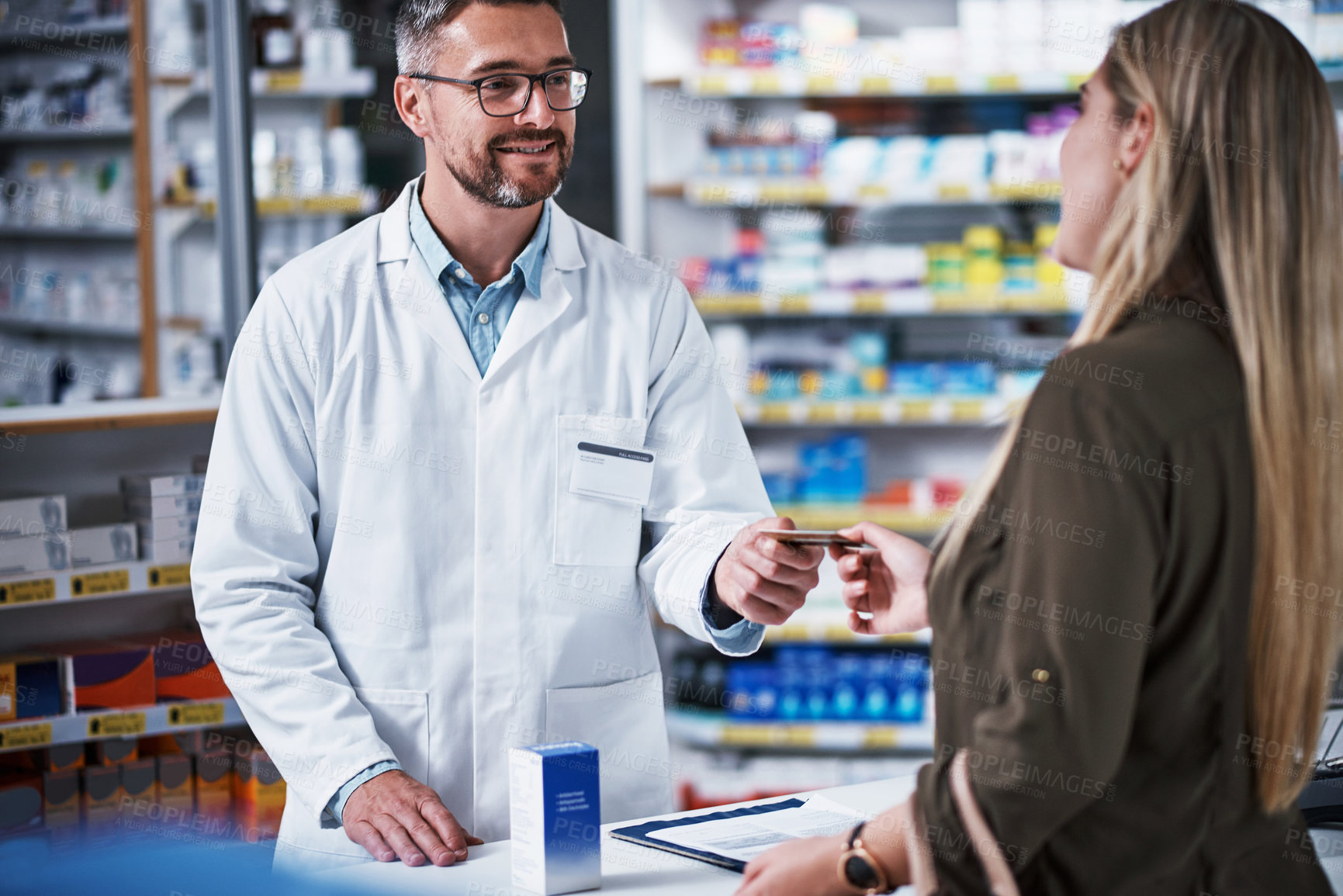 Buy stock photo Shot of a young woman paying for merchandise with a credit card at a pharmacy