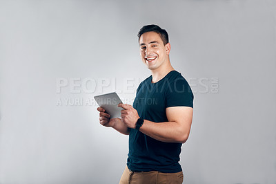 Buy stock photo Studio shot of a handsome young man posing with a tablet against a grey background