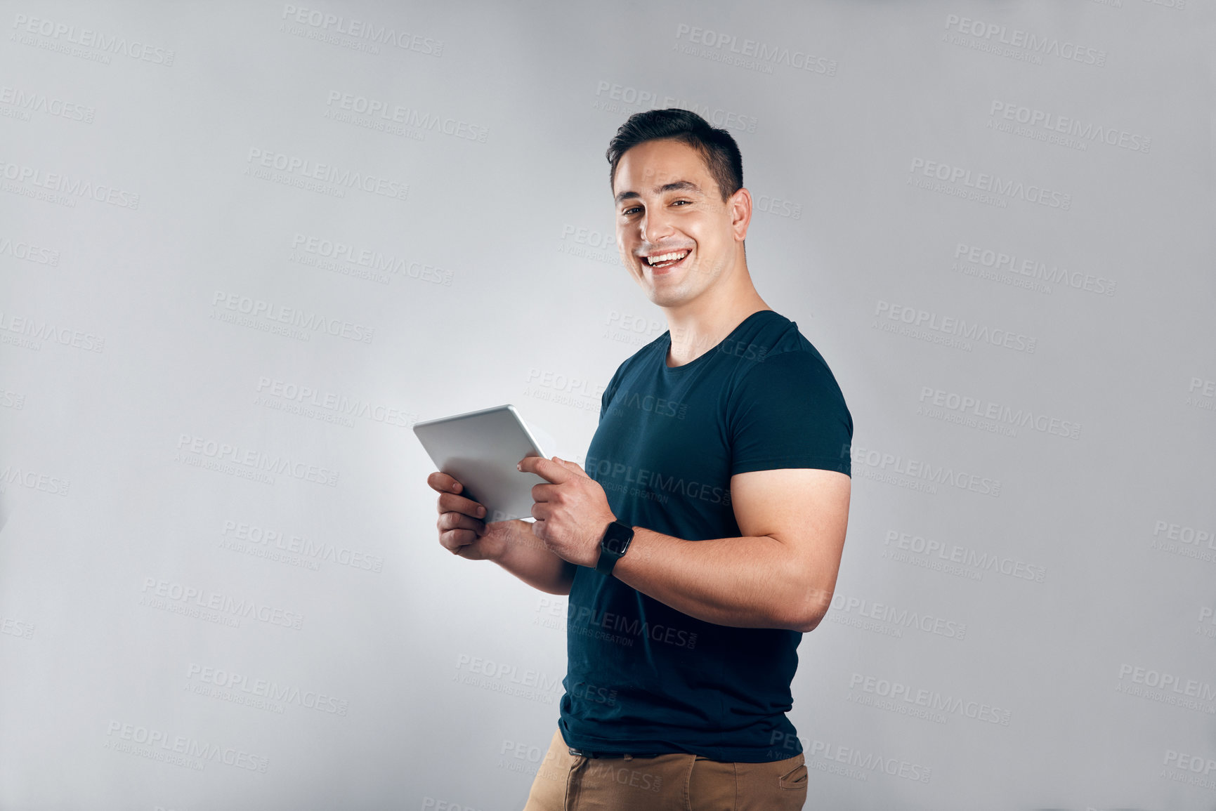 Buy stock photo Studio shot of a handsome young man posing with a tablet against a grey background