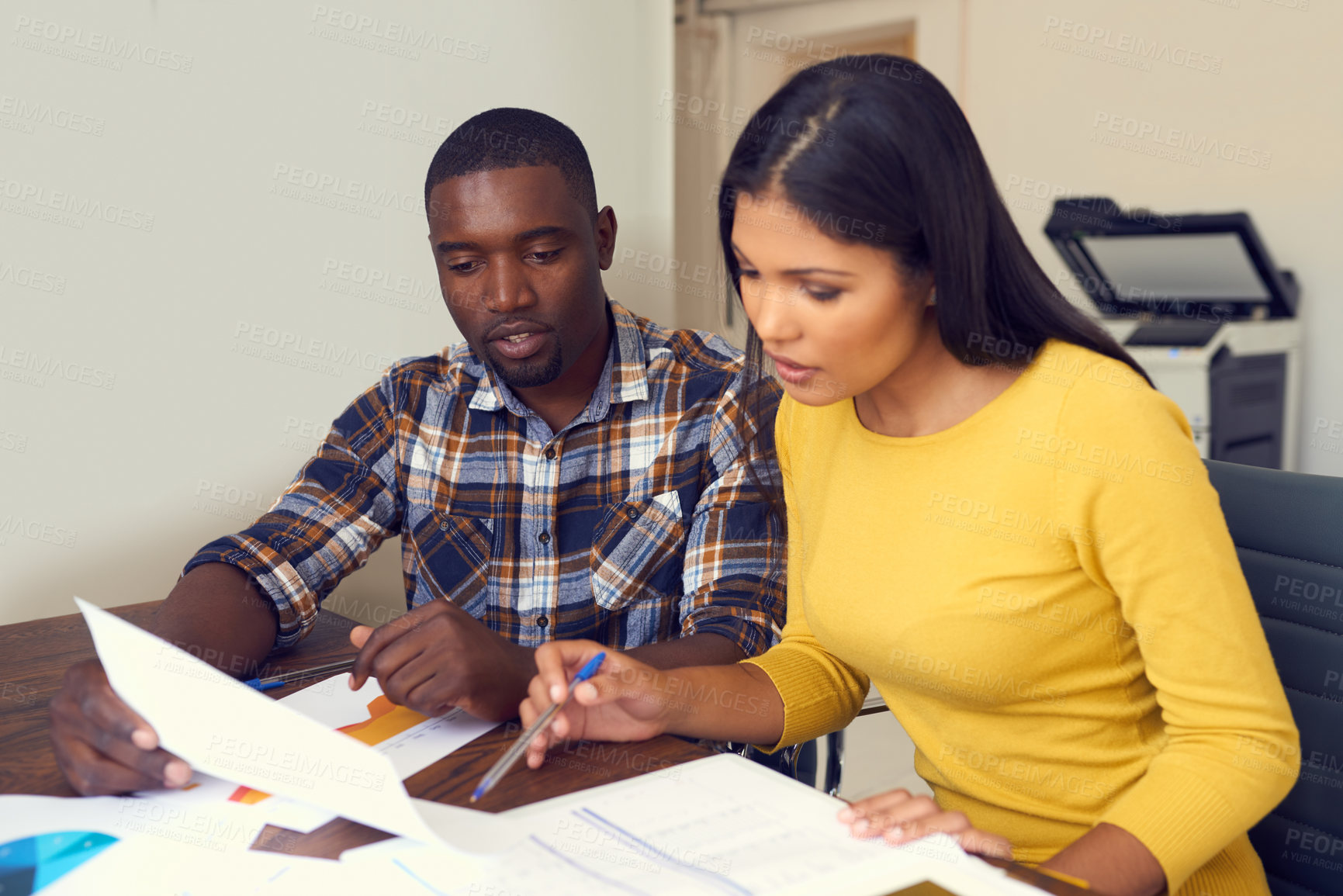 Buy stock photo Shot of a young businessman and businesswoman discussing paperwork in a modern office