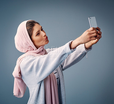 Buy stock photo Studio shot of an attractive young woman taking selfies while standing against a grey background