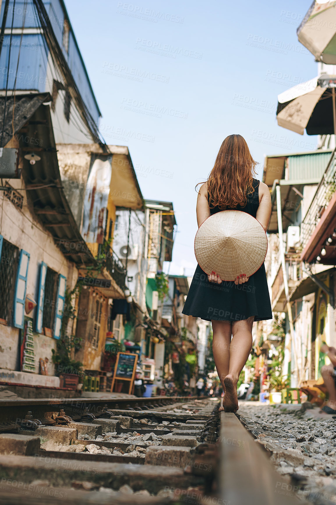 Buy stock photo Rearview shot of a woman walking on a railroad while exploring a foreign city