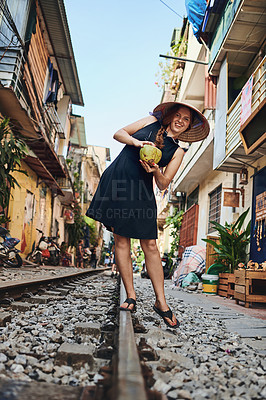 Buy stock photo Shot of a woman having coconut water while out on the train tracks in the streets of Vietnam