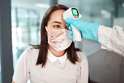 Buy stock photo Shot of a young businesswoman getting her temperature taken with an infrared thermometer in an office