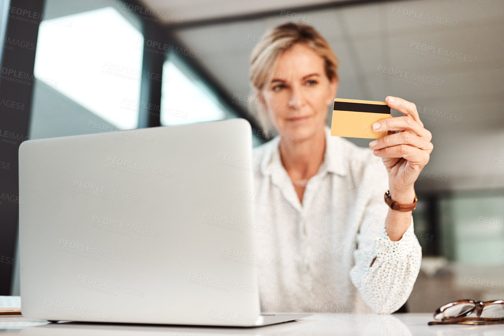Buy stock photo Shot of a mature businesswoman using a laptop and credit card in an office