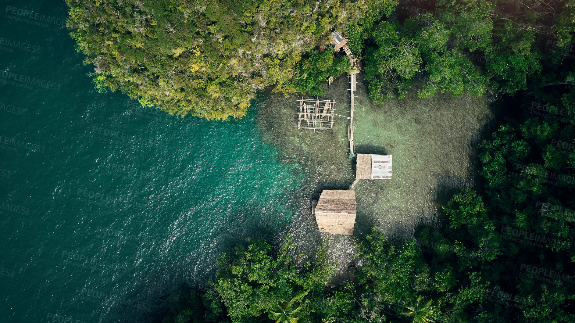 Buy stock photo Drone, ocean and wood building in nature by beach, forest and woods with trees outdoor in Malaysia. Kelong, aerial view and house at sea for fishing, offshore or travel by water in summer environment