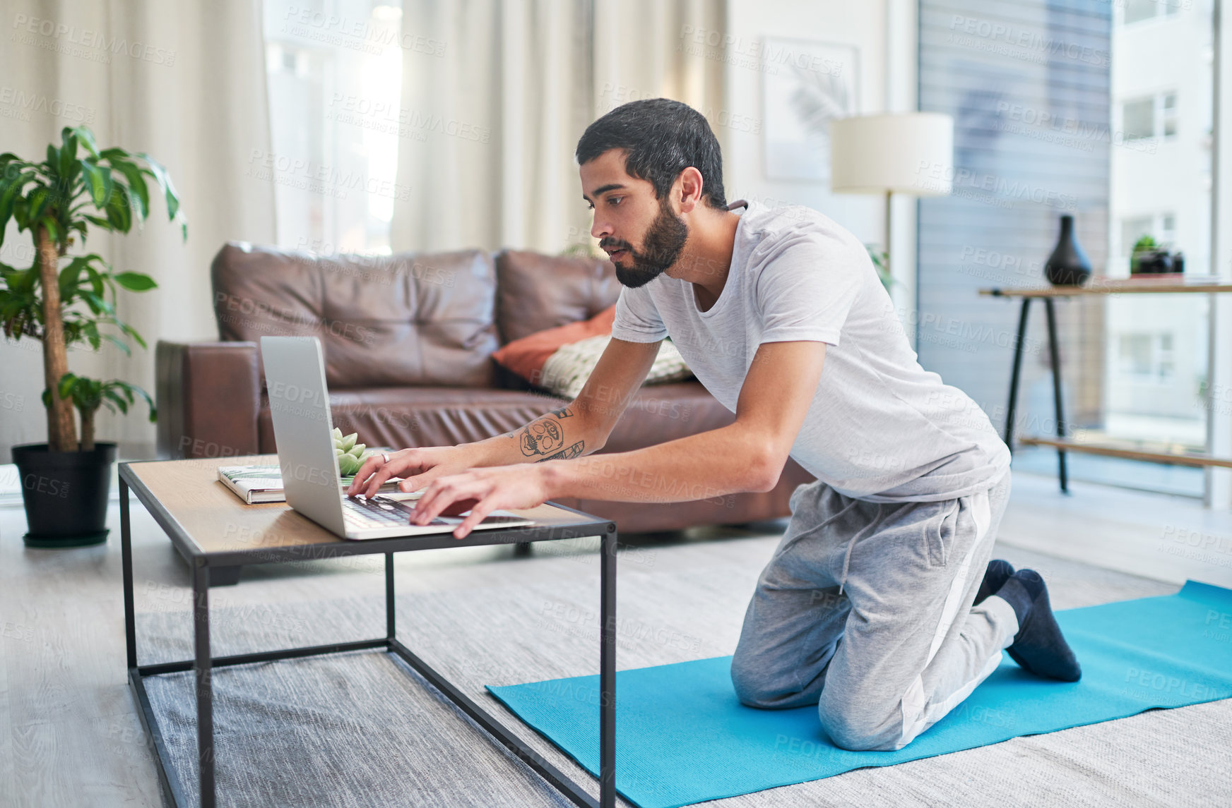 Buy stock photo Shot of a man using his laptop while practising yoga at home