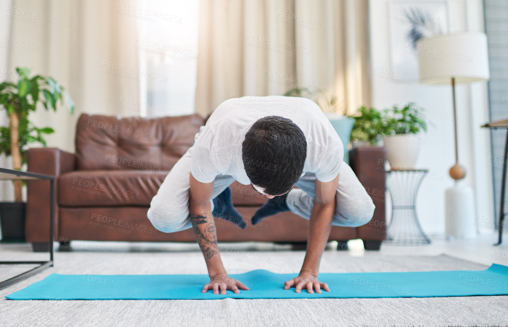 Buy stock photo Shot of a handsome young man practising yoga in his living room at home