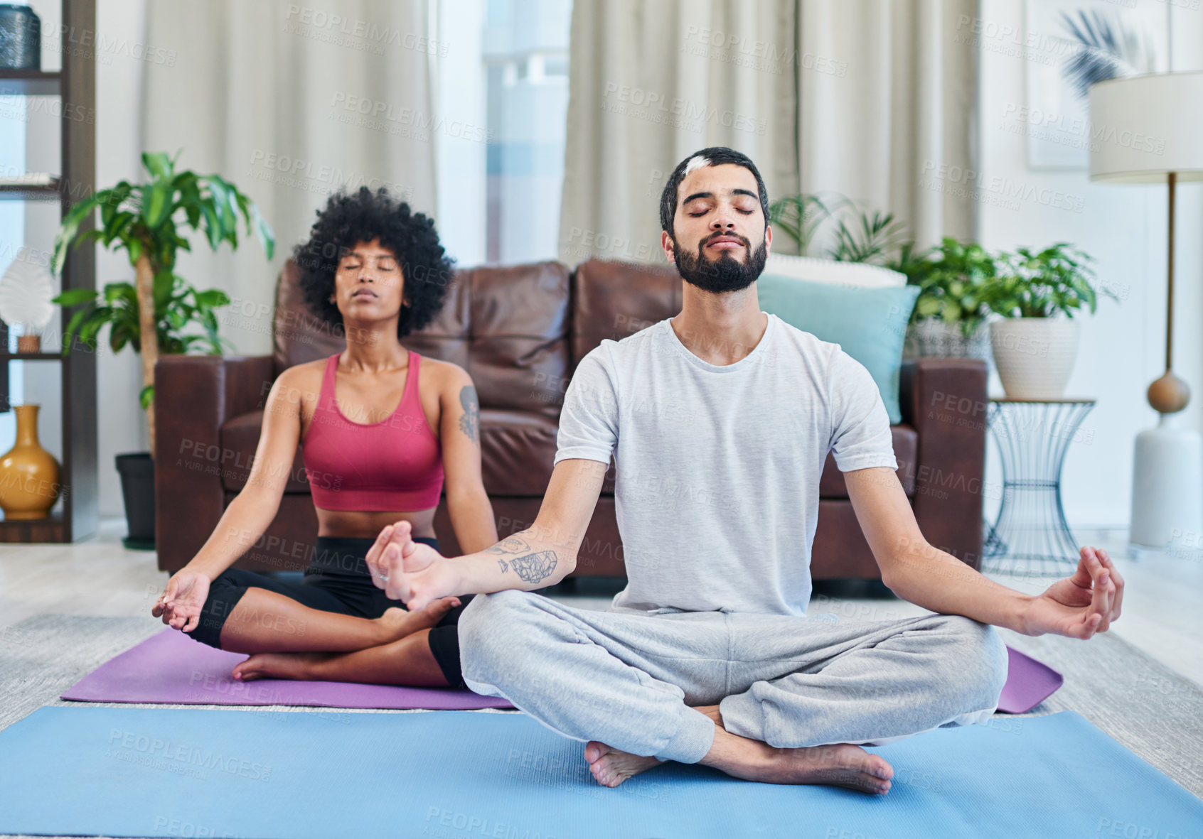 Buy stock photo Shot of a young couple practising yoga in their living room
