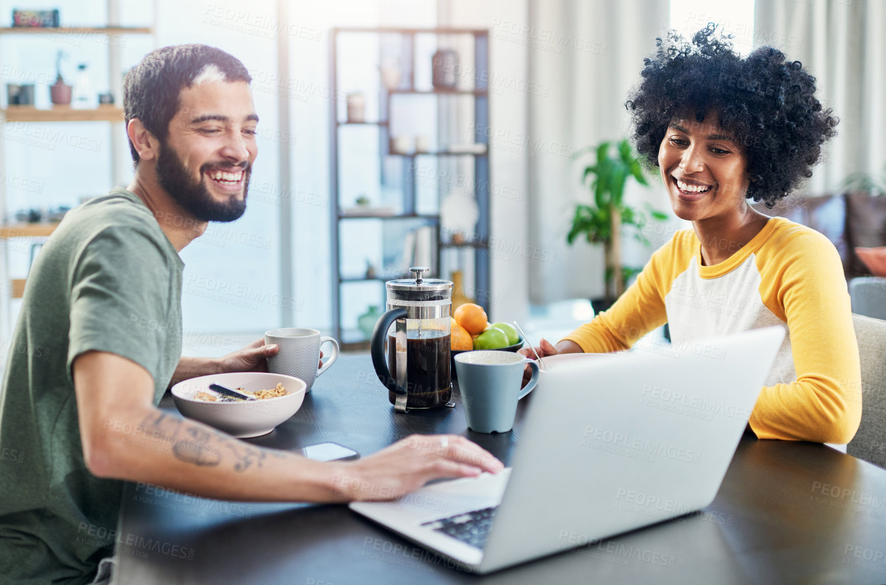 Buy stock photo Shot of a young couple using a laptop while having breakfast at home