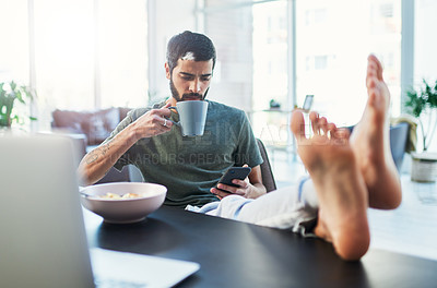 Buy stock photo Shot of a man using his cellphone while having breakfast at home
