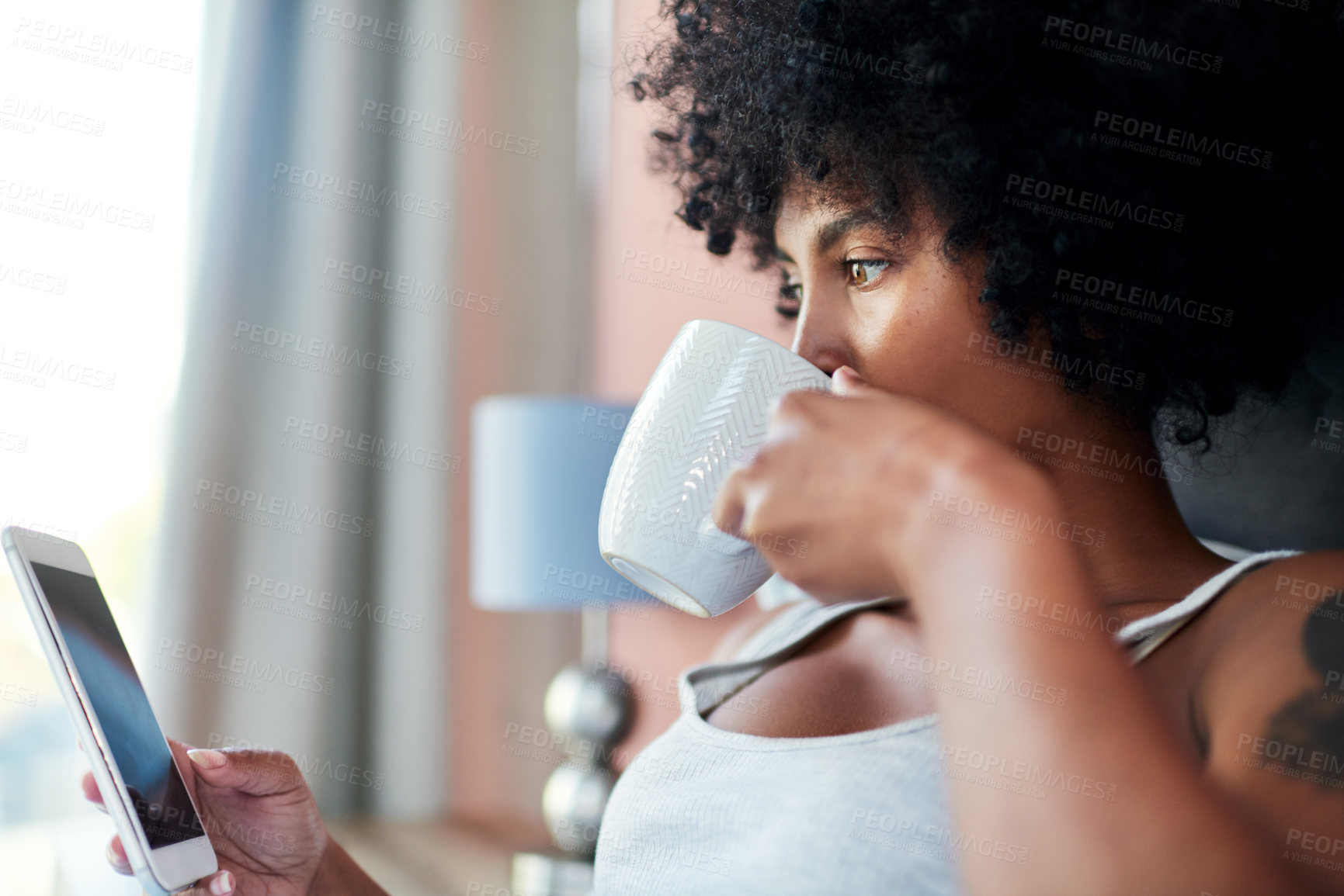 Buy stock photo Cropped shot of a woman using her cellphone while having coffee in bed