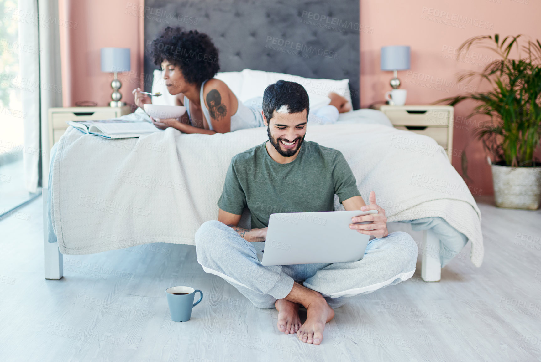 Buy stock photo Shot of a man using his laptop while sitting in the bedroom with his girlfriend