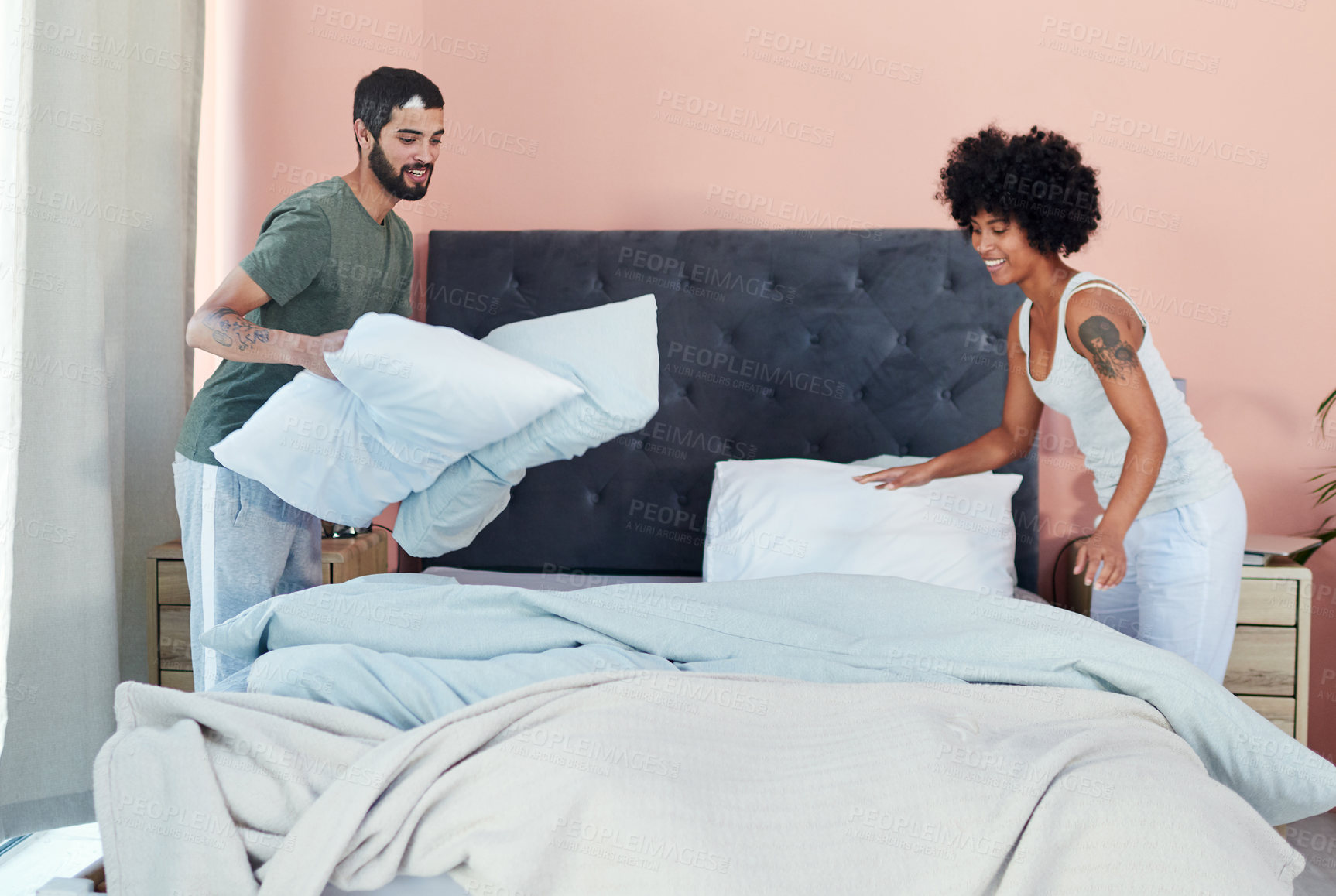 Buy stock photo Shot of a young couple making up their bed