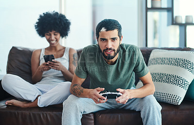 Buy stock photo Shot of a woman using her cellphone while her boyfriend plays video games