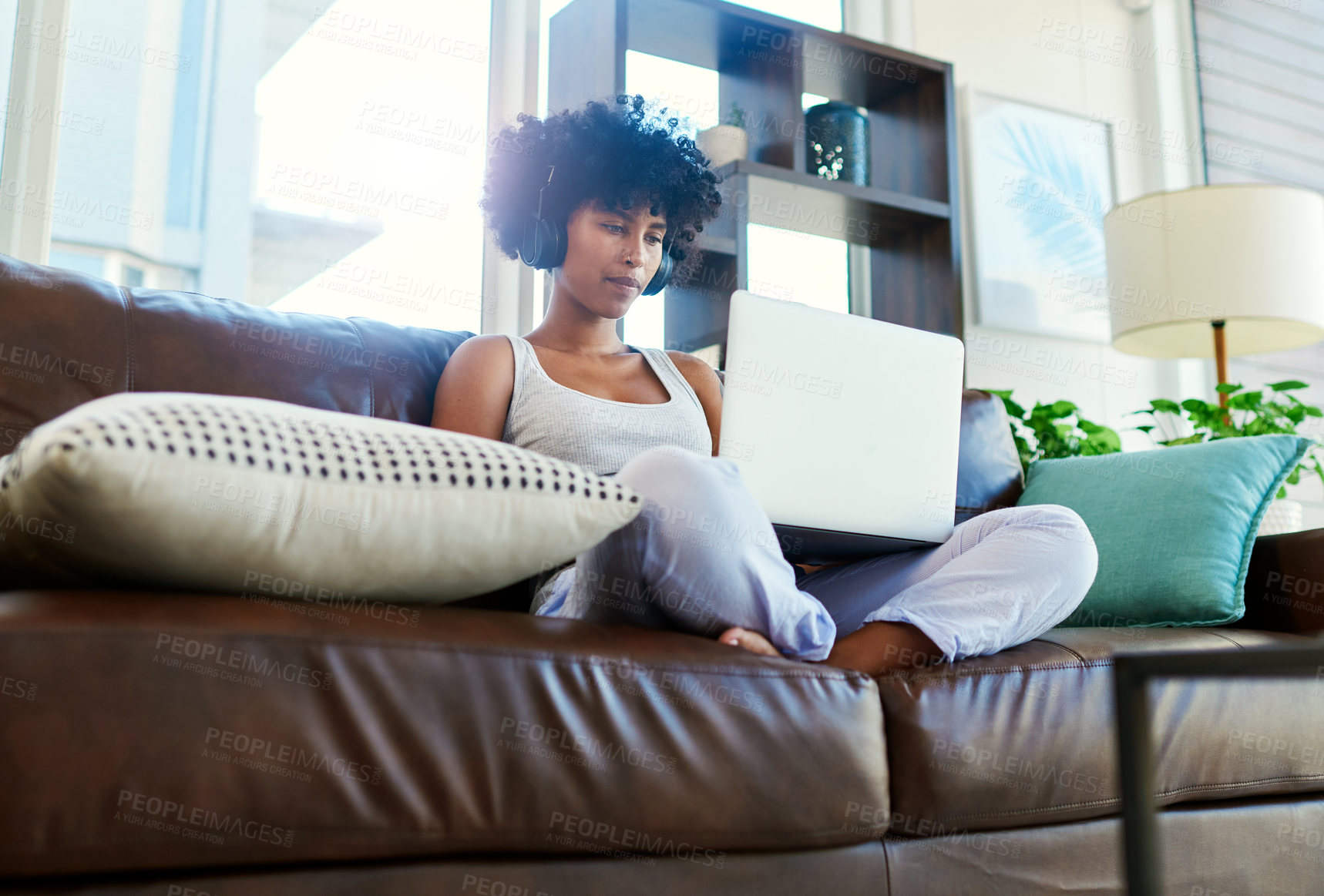 Buy stock photo Shot of a woman using her laptop while sitting on the couch at home
