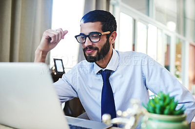 Buy stock photo Shot of a young man using his laptop while working from home