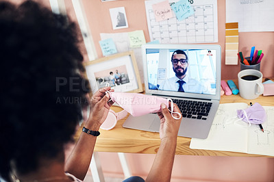Buy stock photo Shot of a woman holding up a face mask while on a conference call at home