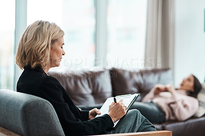 Buy stock photo Shot of a mature psychologist writing notes during a therapeutic session with her patient
