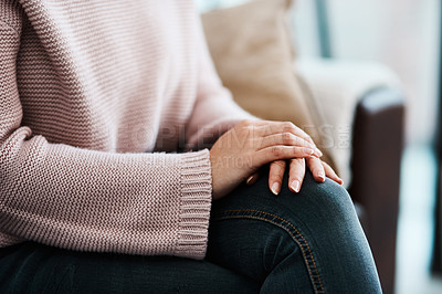 Buy stock photo Cropped shot of a woman sitting on a sofa at home