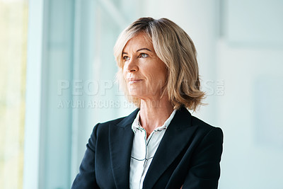 Buy stock photo Shot of a mature psychologist looking out of a window thoughtfully in her office