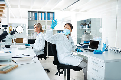 Buy stock photo Shot of a scientist analysing samples in a lab with her colleague in the background