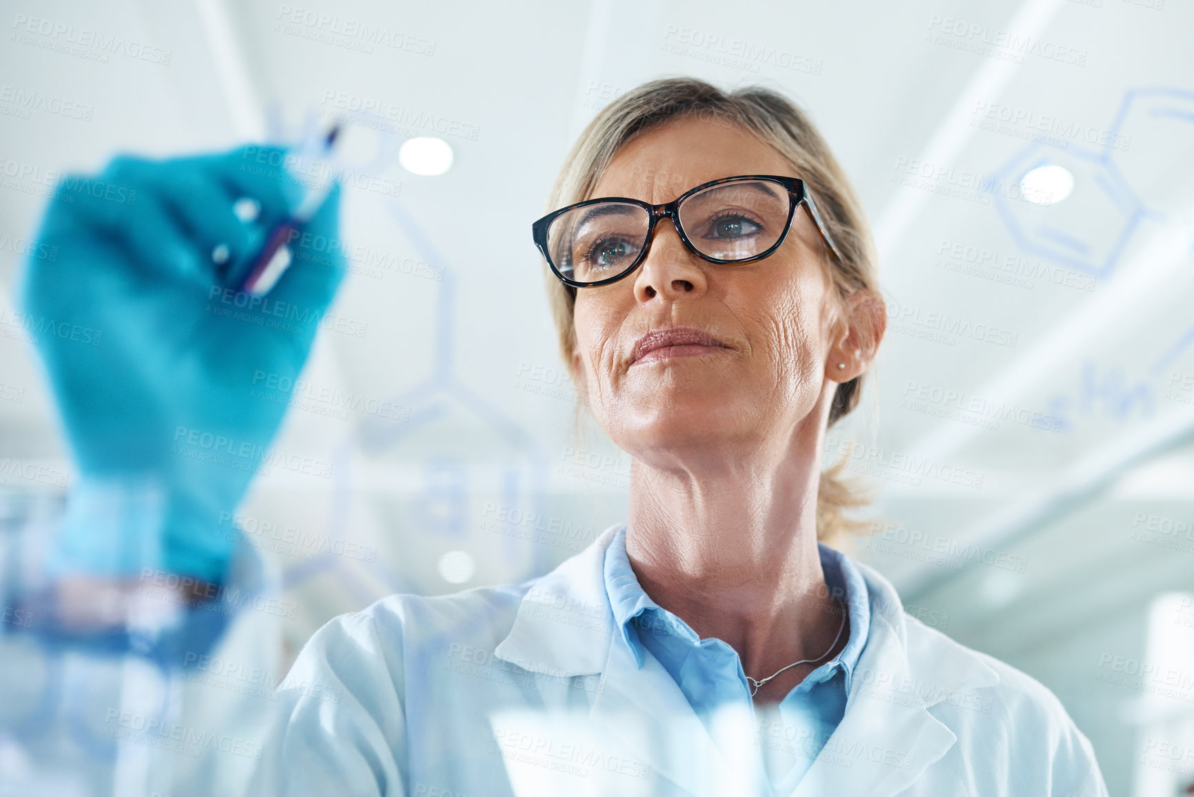 Buy stock photo Shot of a mature scientist drawing molecular structures on a glass wall in a lab