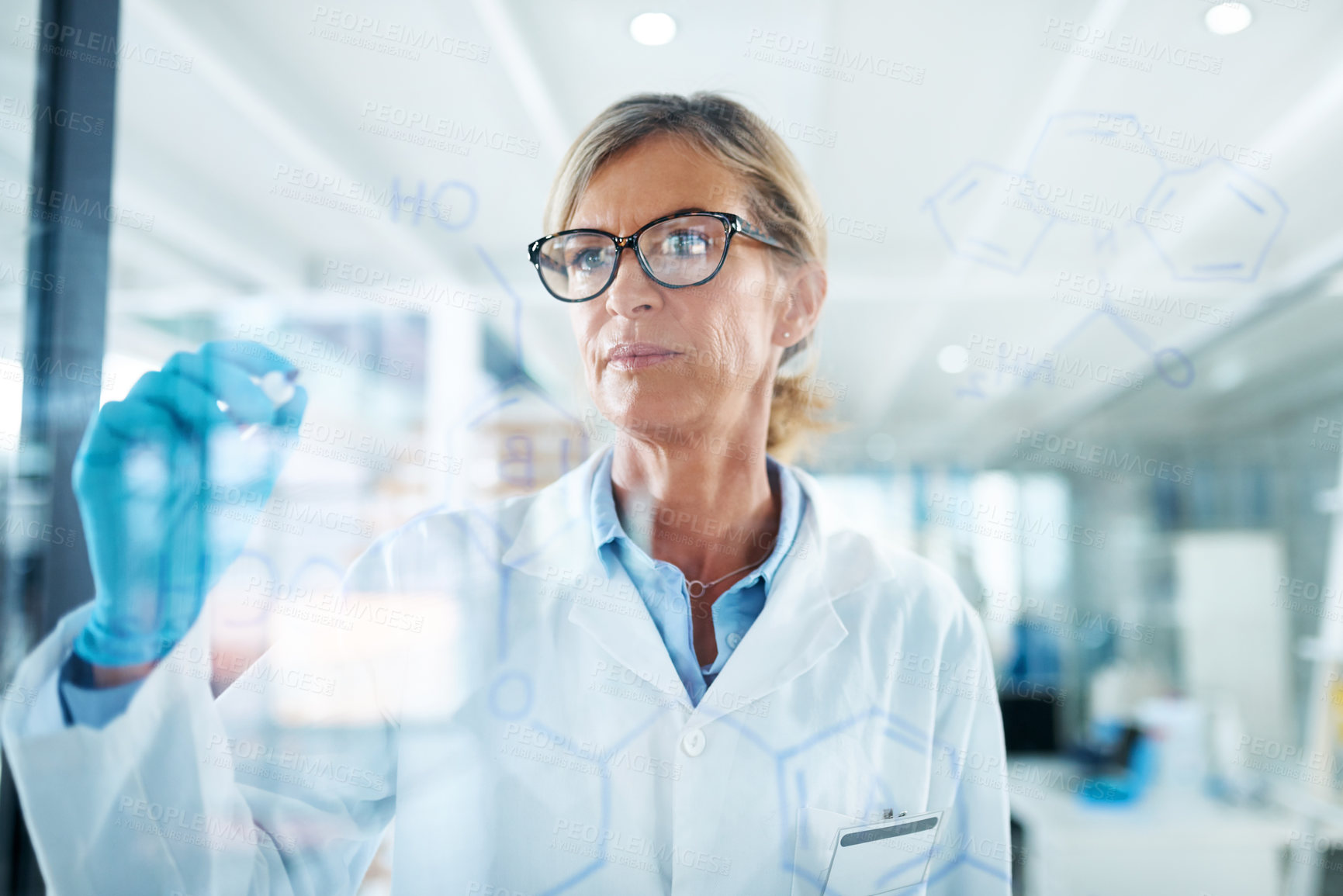 Buy stock photo Shot of a mature scientist drawing molecular structures on a glass wall in a lab
