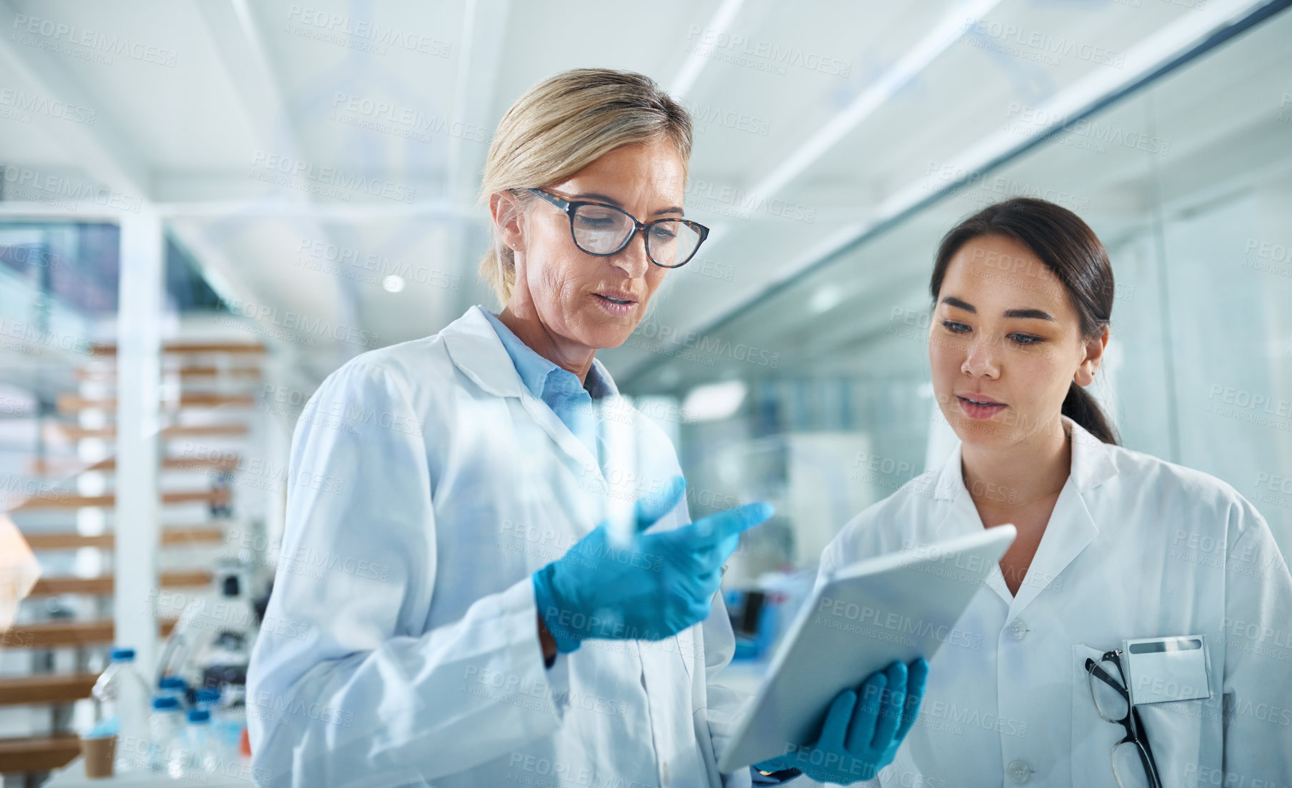 Buy stock photo Shot of two scientists working together on a digital tablet in a lab