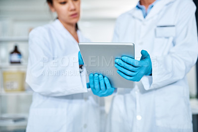 Buy stock photo Closeup shot of two scientists working together on a digital tablet in a lab