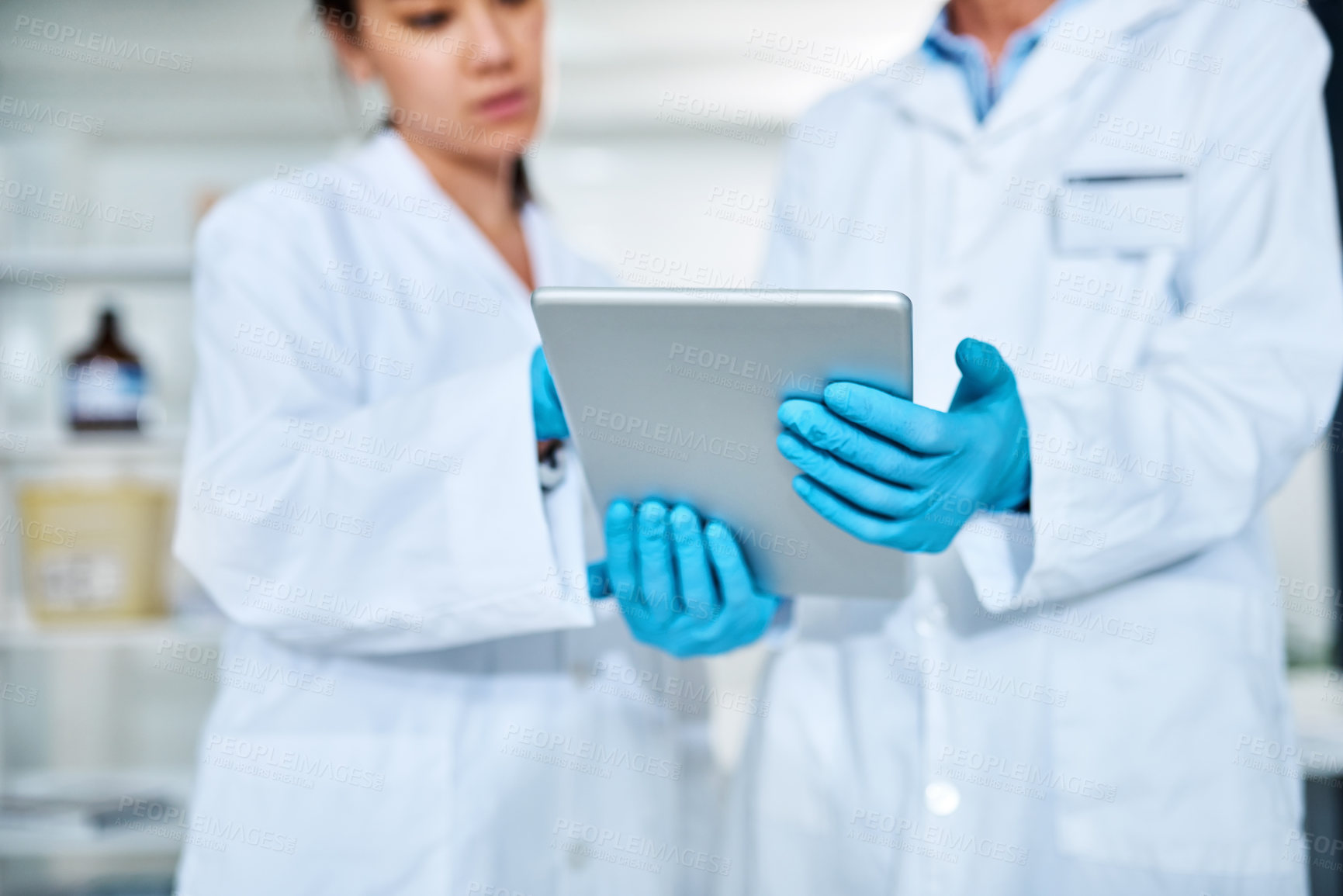 Buy stock photo Closeup shot of two scientists working together on a digital tablet in a lab