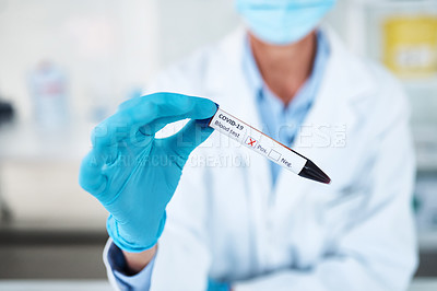 Buy stock photo Closeup shot of an unrecognisable scientist holding a blood filled test tube with a positive Covid-19 result on its label