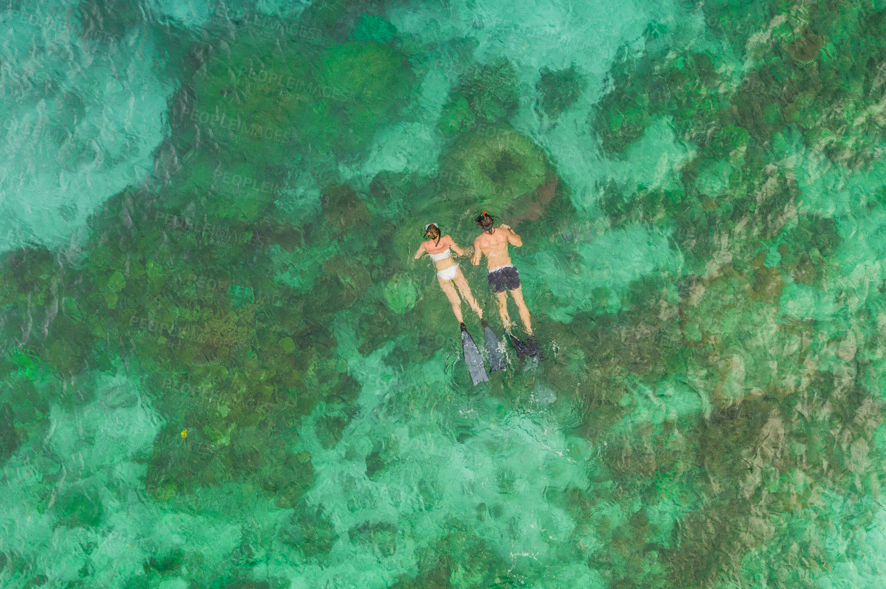 Buy stock photo High angle shot of an unrecognizable couple swimming in the waters of Raja Ampat