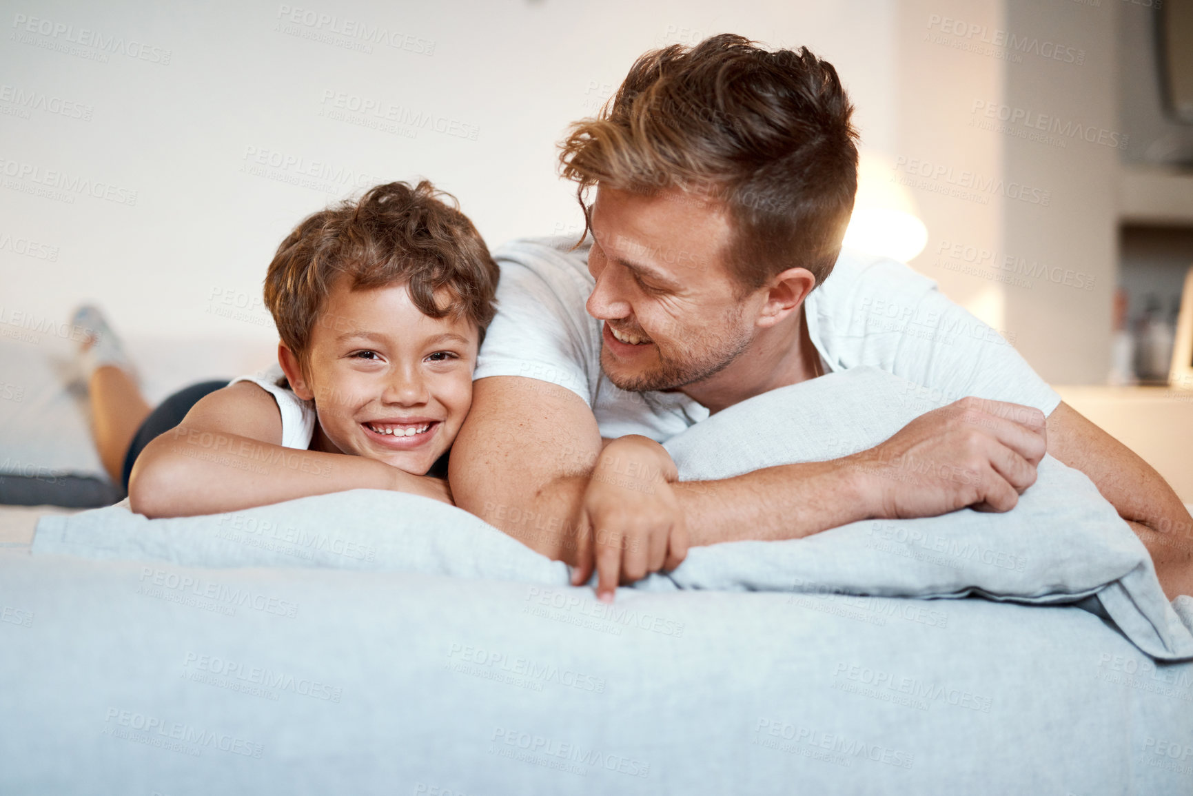 Buy stock photo Shot of a man and his son lying on a bed together