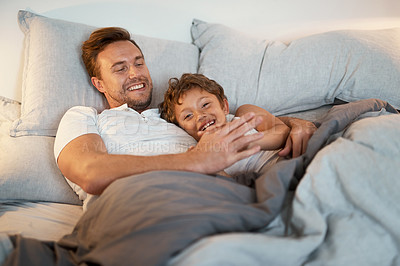 Buy stock photo Shot of a man and his son lying in a bed together