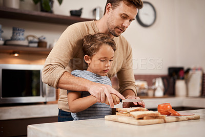 Buy stock photo Shot of a young boy making a sandwich with the help of his father