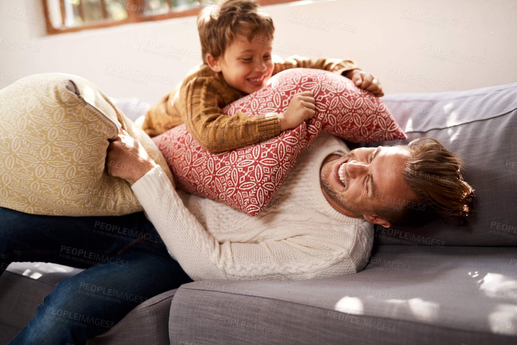 Buy stock photo Shot of a man and his young son having a pillow fight on the sofa at home