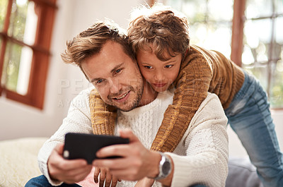 Buy stock photo Cropped shot of a man taking a selfie with his son at home