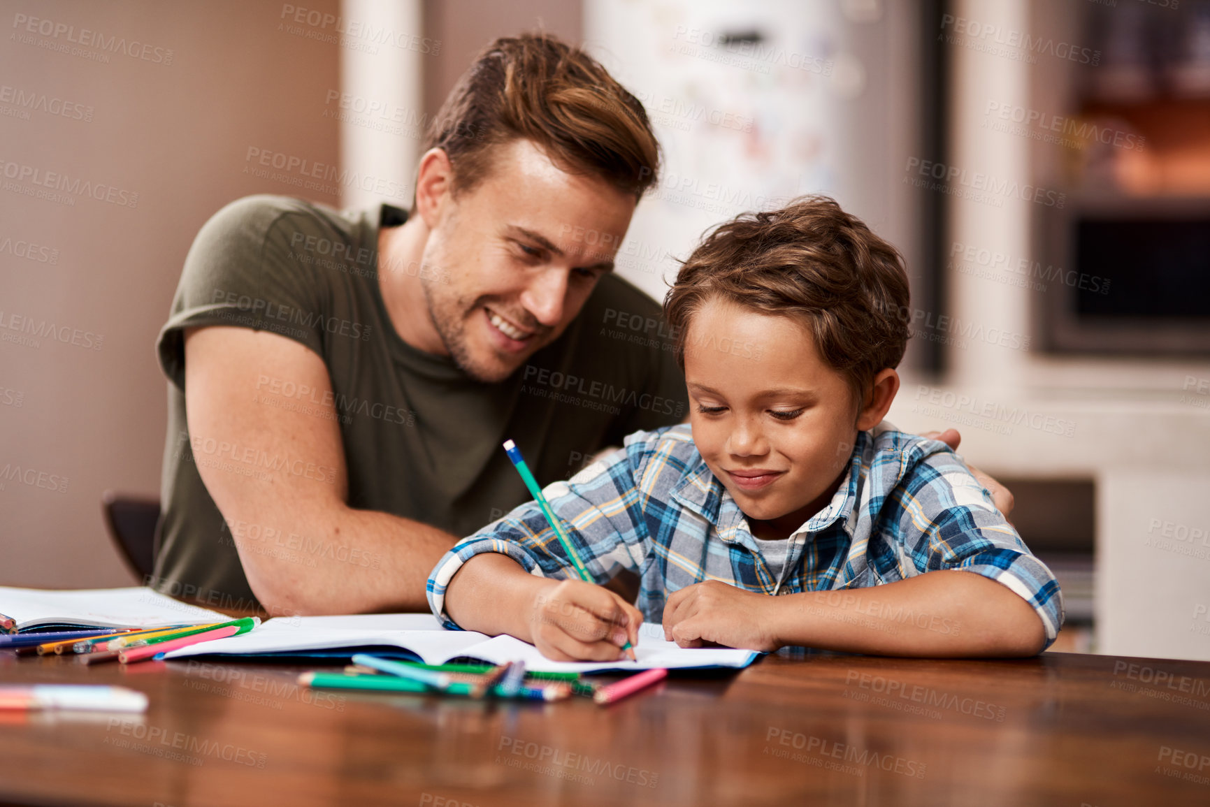 Buy stock photo Shot of a man sitting with his son while he does his homework