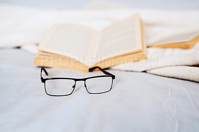 Buy stock photo Still life shot of reading glasses and books lying on a bed