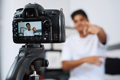 Buy stock photo Cropped shot of a young man using a camera on a tripod to record himself at home