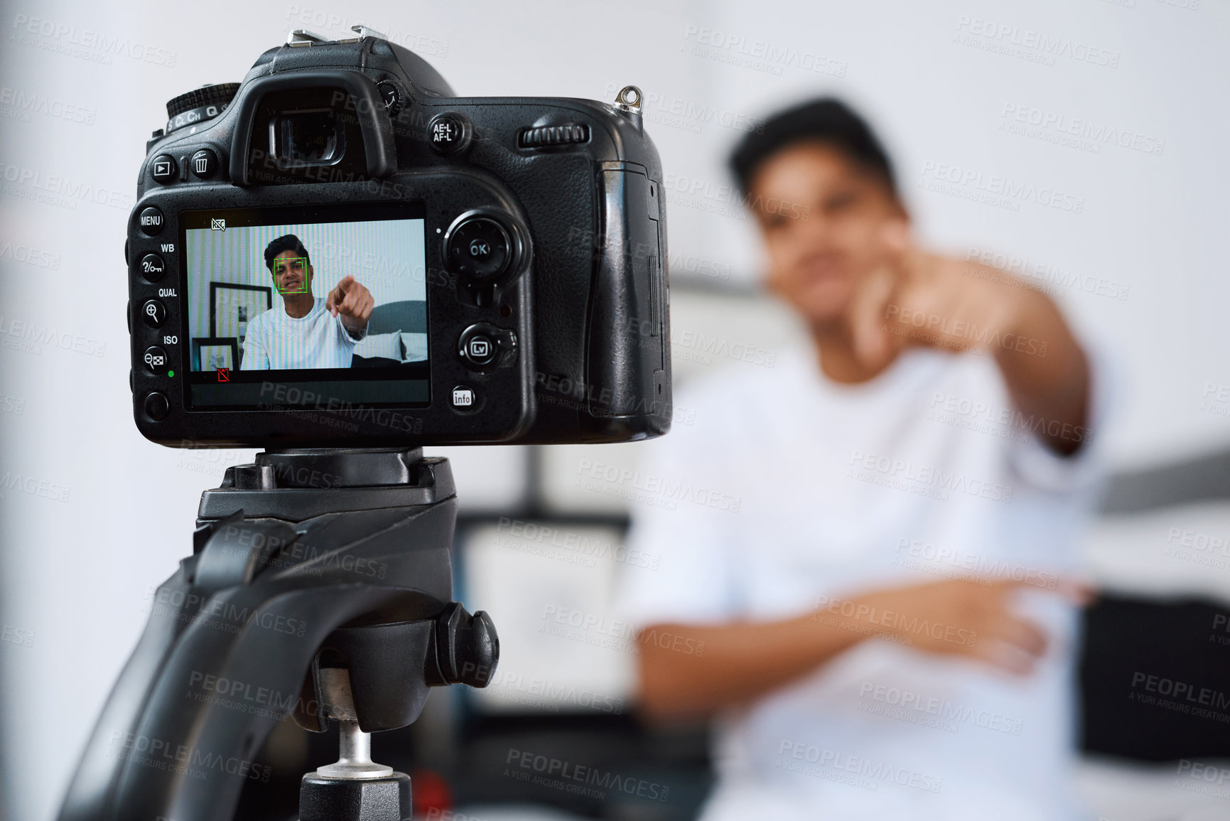 Buy stock photo Cropped shot of a young man using a camera on a tripod to record himself at home