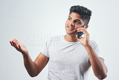 Buy stock photo Studio shot of a young man talking on his cellphone while standing against a white background