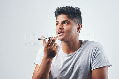 Buy stock photo Studio shot of a young man talking on his cellphone while standing against a white background