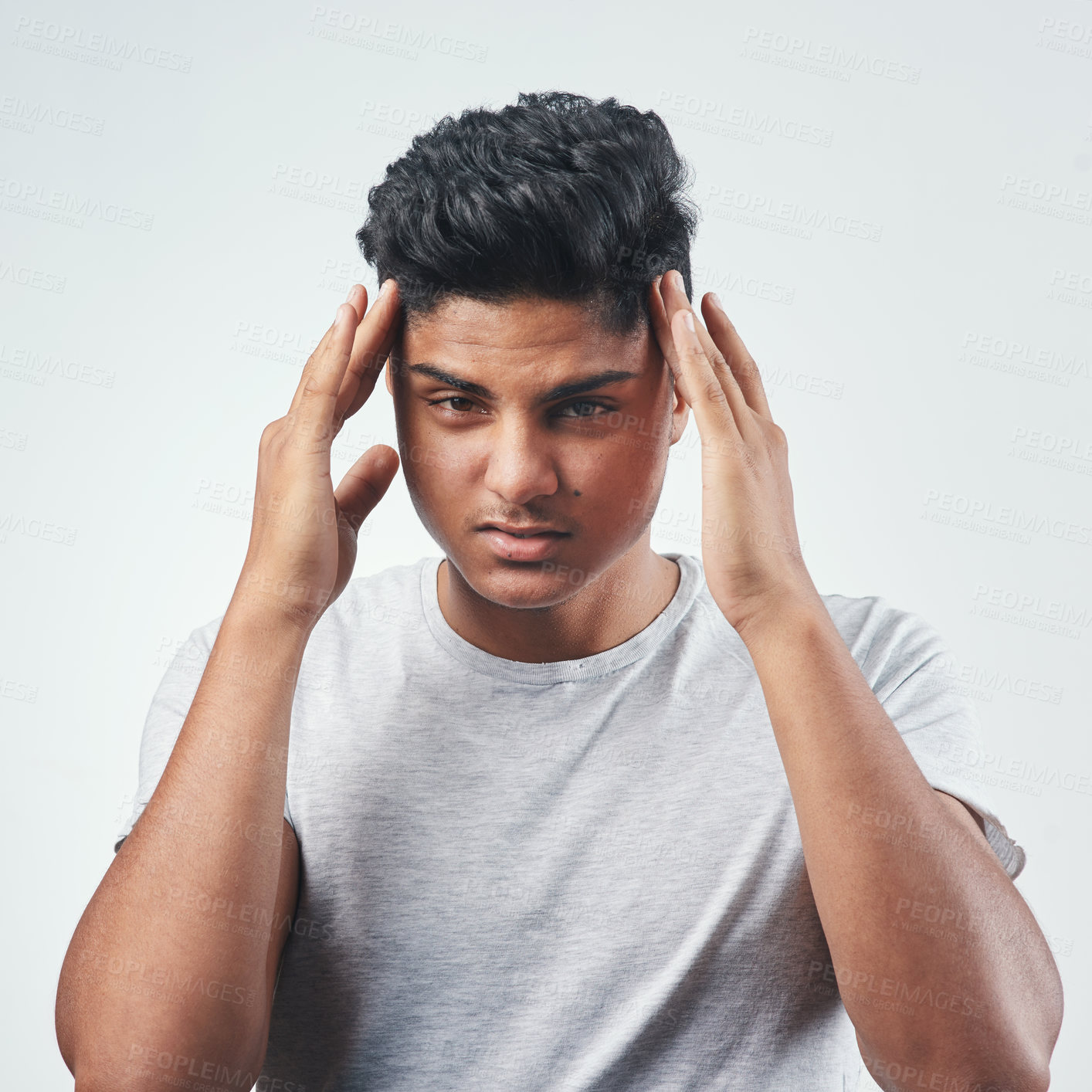 Buy stock photo Studio shot of a young man suffering from a headache while standing against a white background