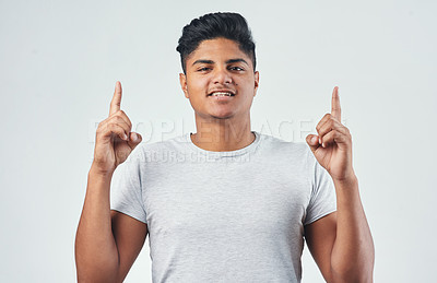Buy stock photo Studio shot of a young man pointing at something against a white background